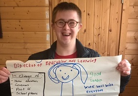 A boy holding up a poster he has made of the Director of Education and Learning