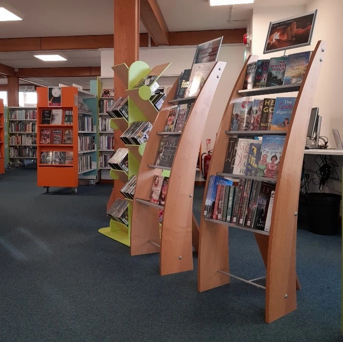 This is a picture of frees standing book shelves filled with books to the right and more bookshelves behind and to the left.