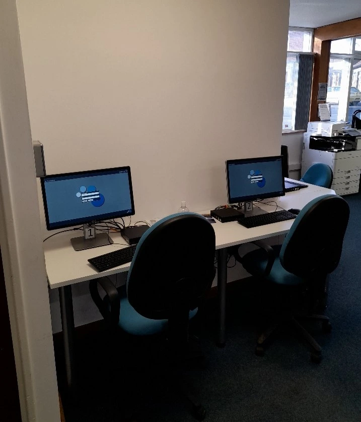 This is a picture of a desk with two computer screens and keyboards and two chairs in front of desk.