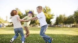 Three children playing and holding hands in a circle