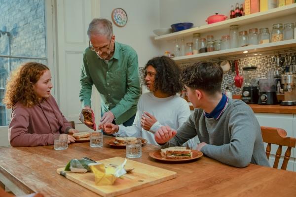 a foster carer is having breakfast with three young people.