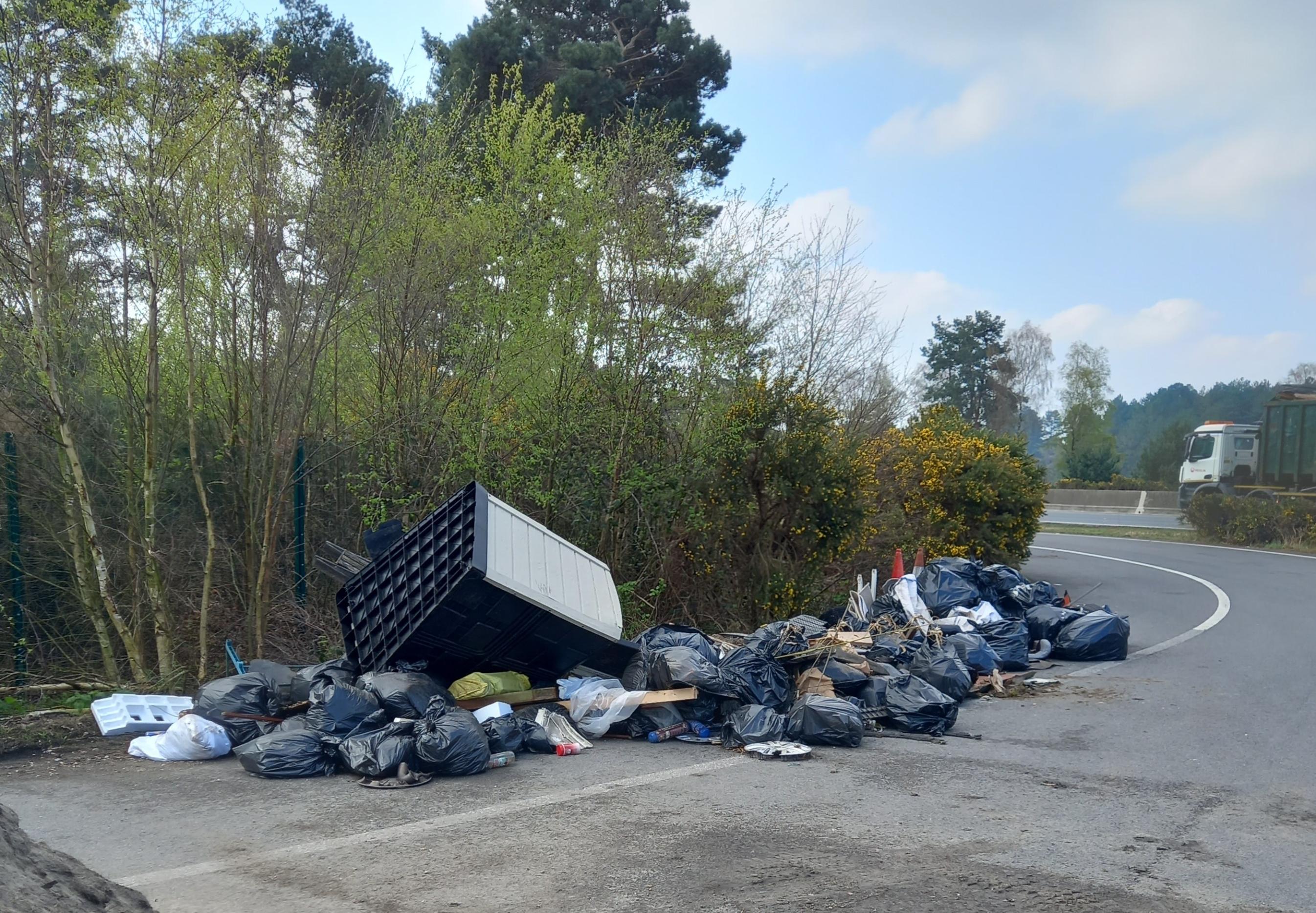 A pile of black bin bags full of rubbish collected from the highway