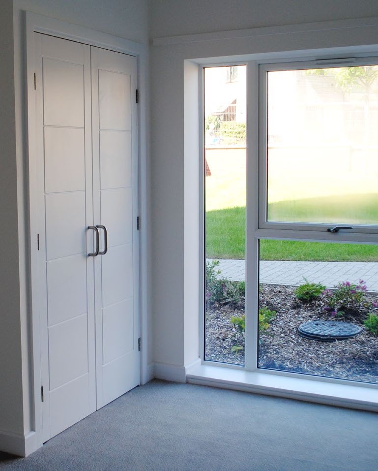 St martins house interior, a window looking out over some grass and cupboard doors with a grey carpet