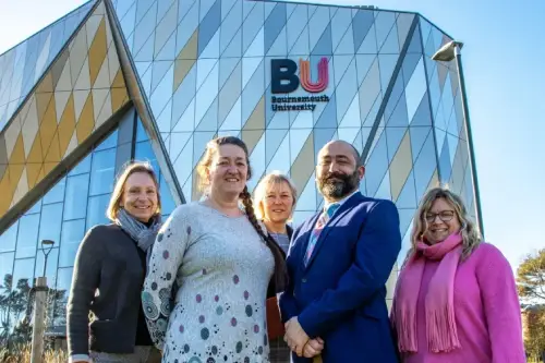 A group of people standing in front of Bournemouth University building.