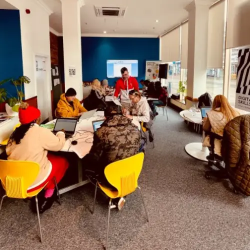 People sitting in groups, using their laptops.