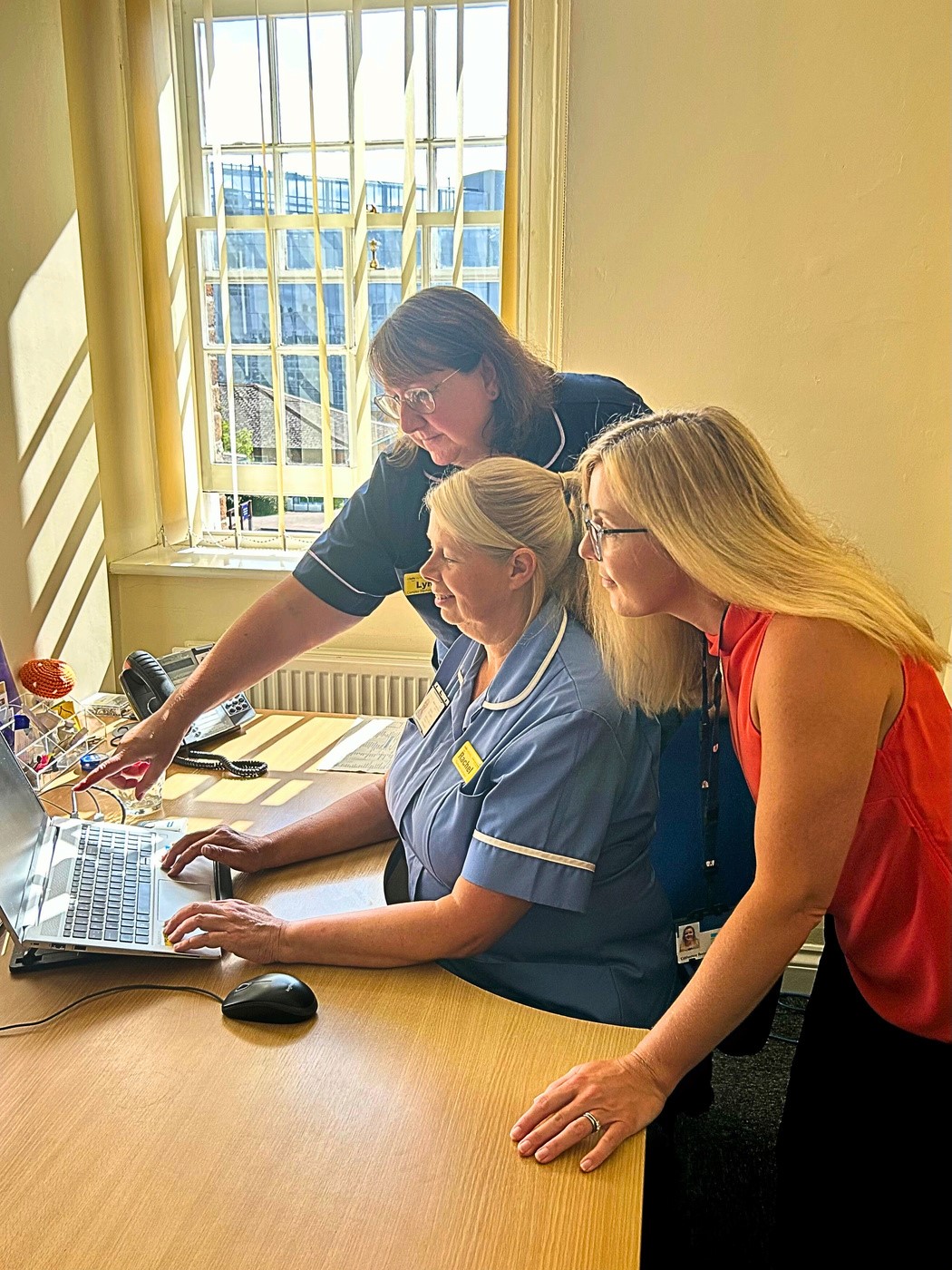 Catherine Ronzitti helping someone who is using a computer.