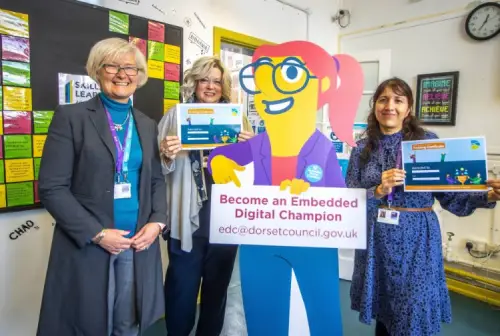 3 people standing around a 'Become an Embedded Digital Champion' carboard cutout