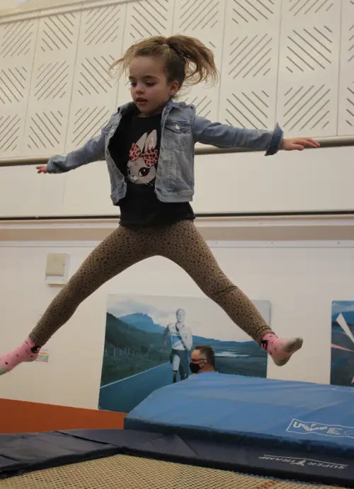 a girl juming on a trampoline.