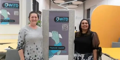 2 women standing by the WiTD Women in Tech Dorset poster.