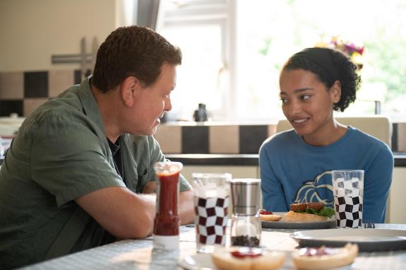 Mike is sitting with Zara at the kitchen table. He's given her her favourite meal and they're talking