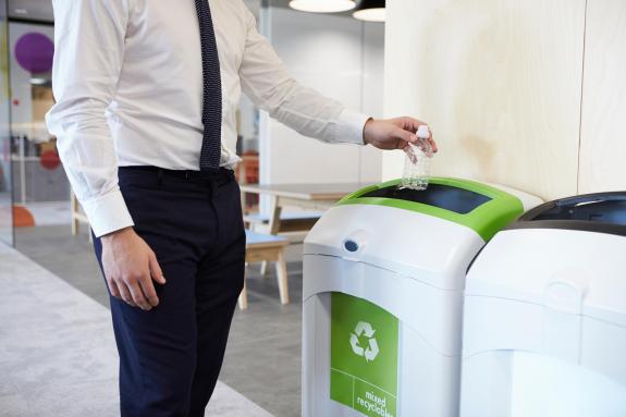 Office worker placing plastic bottle in recycling bin