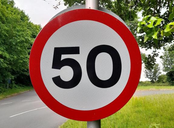 A circular sign outlined in red with the figure 50 in the centre adjacent to a road